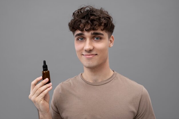 Jeune homme tenant une bouteille de sérum