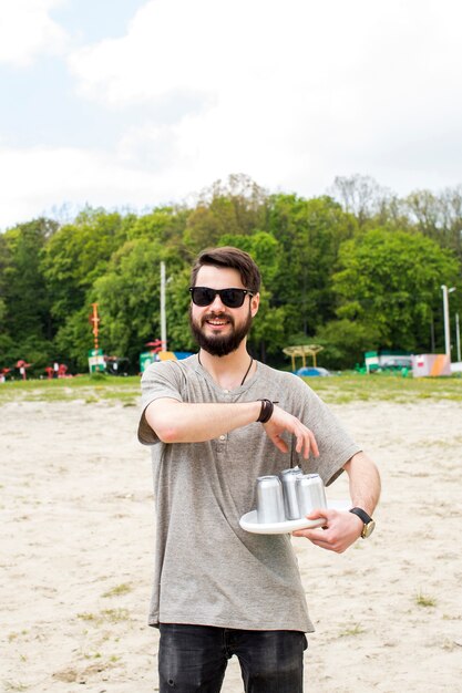 Jeune homme tenant des canettes de bière