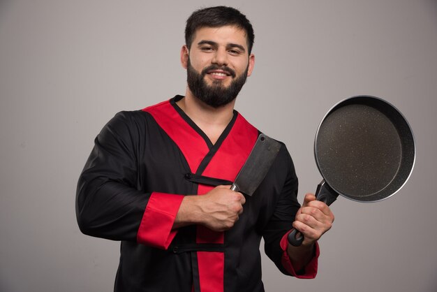 Jeune homme tenant dans la main une casserole sombre.