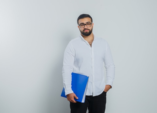 Jeune homme tenant le dossier en chemise blanche, pantalon et beau