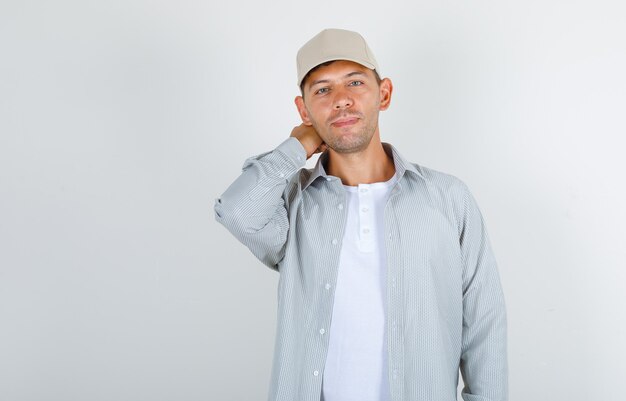 Jeune homme tenant la main derrière sa tête en t-shirt et casquette