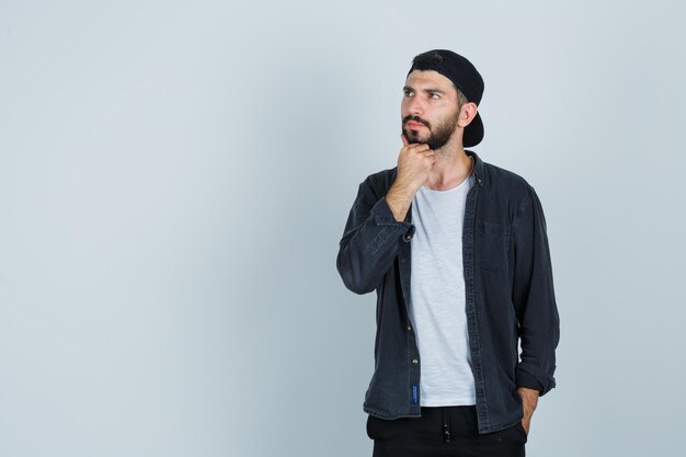 Jeune homme tenant la main sous le menton et à la pensive