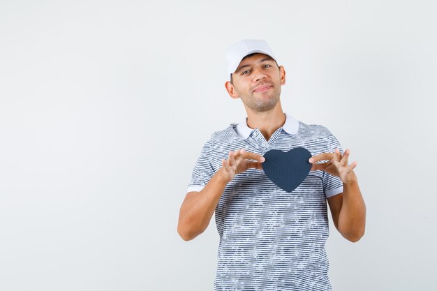 Jeune homme tenant présent fort en t-shirt et casquette et à la joyeuse