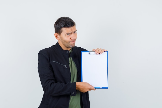 Jeune homme tenant le presse-papiers en t-shirt, vue de face de la veste.