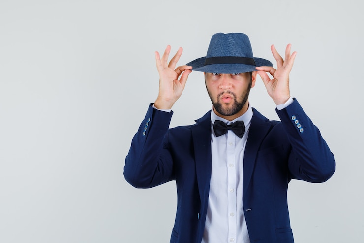 Photo gratuit jeune homme tenant son chapeau en costume et regardant beau, vue de face.