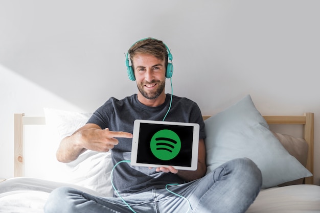 Jeune homme tenant une tablette avec l&#39;application Spotify