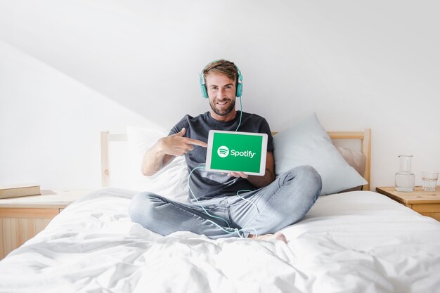 Jeune homme tenant une tablette avec l&#39;application Spotify