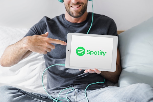 Photo gratuite jeune homme tenant une tablette avec l'application spotify