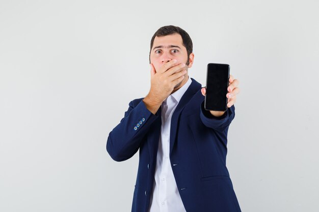 Jeune homme tenant un téléphone mobile en chemise