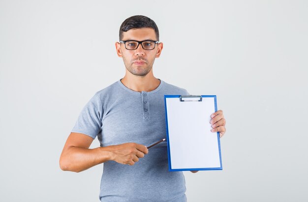 Jeune homme, tenue, presse-papiers, et, crayon, dans, t-shirt gris, lunettes