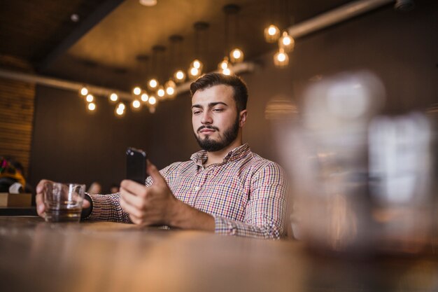 Jeune homme, tenue, verre boisson, à, téléphone portable