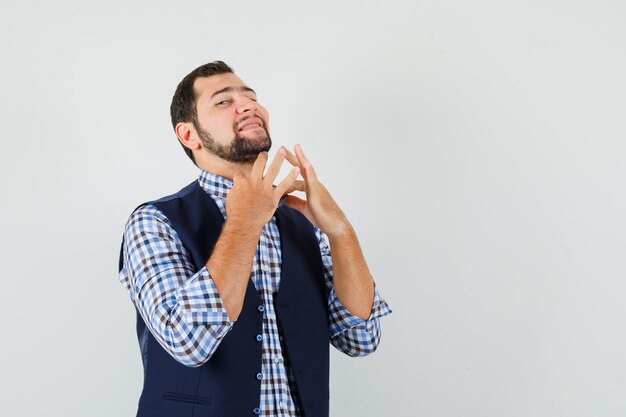 Jeune homme tirant son col en chemise, gilet et à la confiance