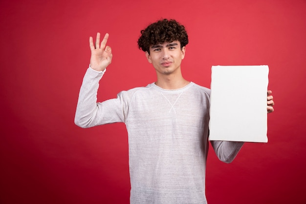 Jeune homme avec une toile vide donnant un signe ok.