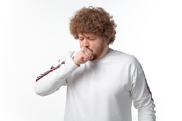 Jeune homme toussant sur un mur blanc