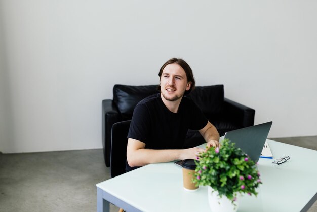 Jeune homme travaillant à la maison avec un ordinateur portable et des papiers sur le bureau