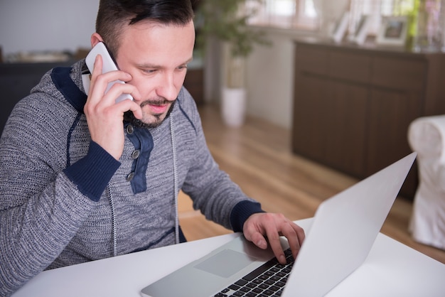 Jeune homme travaillant à la maison avec son ordinateur portable