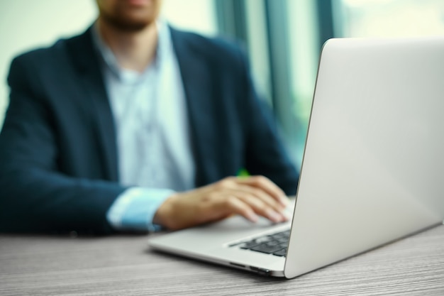 Jeune homme travaillant avec un ordinateur portable, les mains de l'homme sur un ordinateur portable, homme d'affaires au lieu de travail