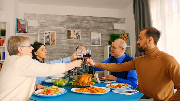 Photo gratuite jeune homme trinquant avec sa famille tout en savourant un dîner.