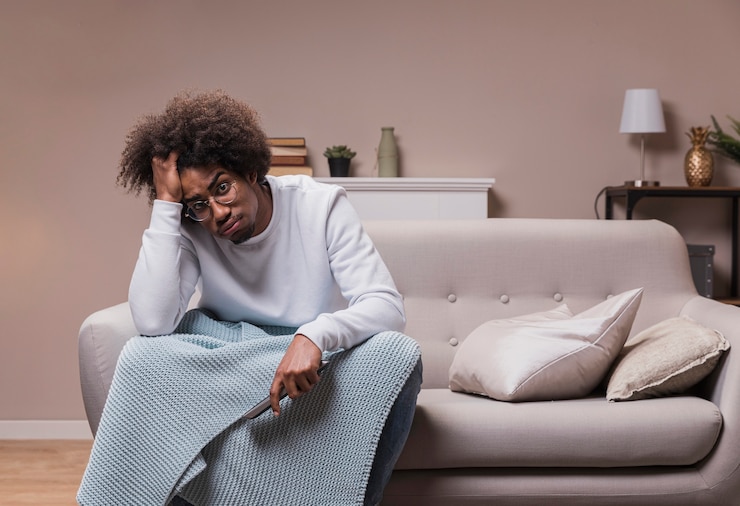 Photo gratuit jeune homme triste sur canapé avec télécommande