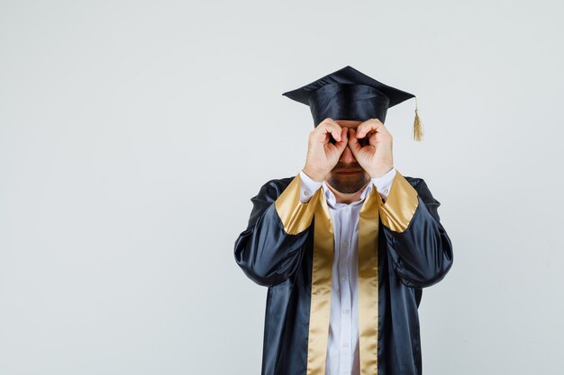 Jeune homme en uniforme d'études supérieures montrant le geste de lunettes et à la vue de face, focalisée.