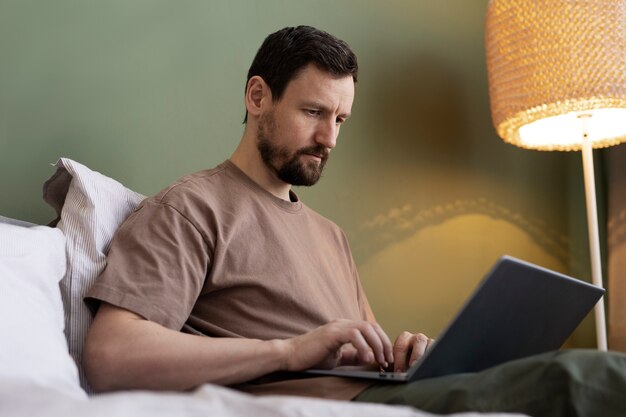 jeune homme, utilisation, ordinateur portable, lit