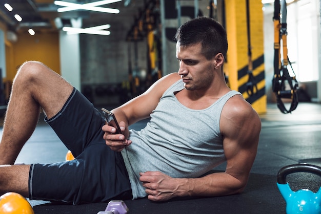 Jeune homme, utilisation, téléphone portable, dans, gymnase