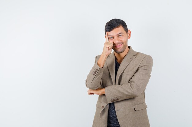 Jeune homme en veste marron grisâtre posant et à la vue impressionnante, de face.