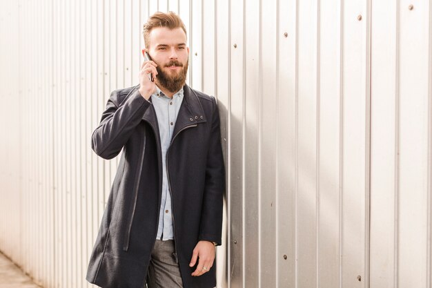 Jeune homme en veste noire parlant sur téléphone portable