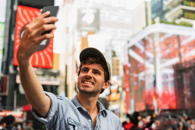 Jeune homme en ville prenant selfie