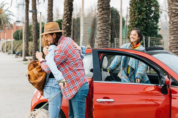 Jeune homme voeux femme près de voiture rouge