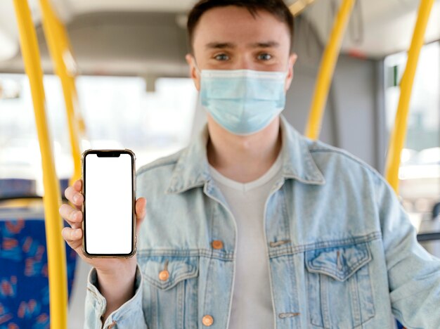 Jeune homme voyageant en bus de la ville montrant smartphone avec écran blanc