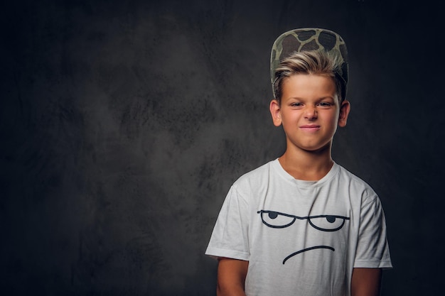 Jeune hooligan effronté en casquette pose pour le photographe au studio photo sur fond sombre.