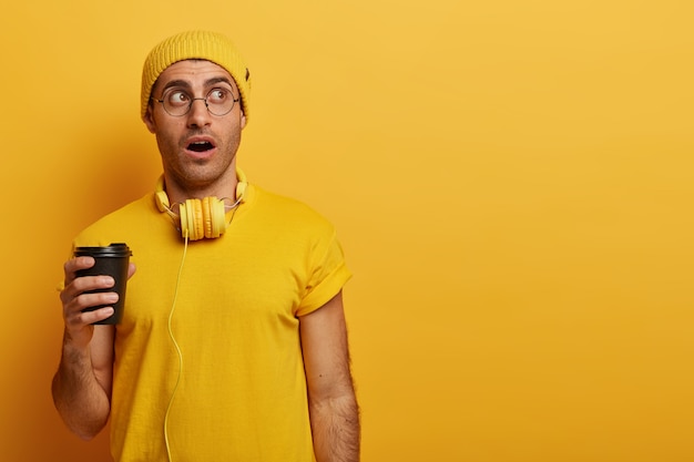 Un jeune impressionnant reste sans voix, porte un chapeau jaune et un t-shirt décontracté