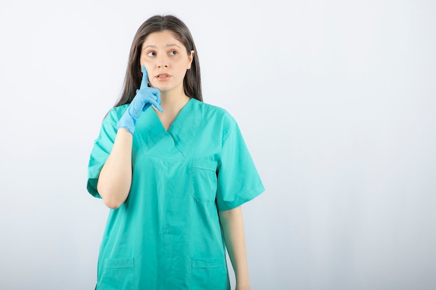 jeune infirmière pensive debout et détournant les yeux.