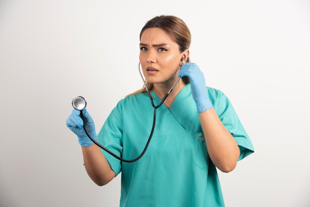 Jeune infirmière avec stéthoscope sur fond blanc