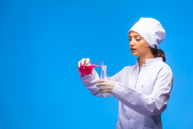 Une jeune infirmière en uniforme blanc fait un test de virus très attentivement.