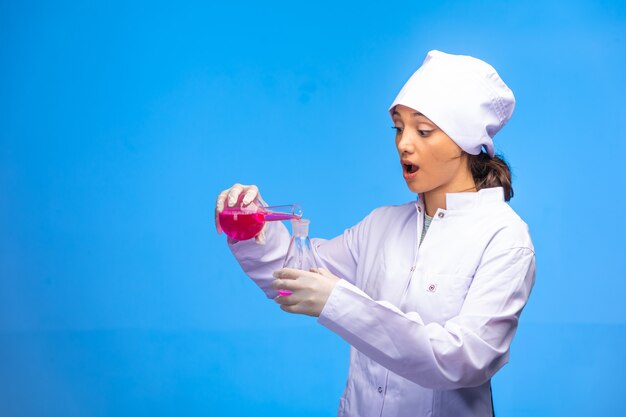 Une jeune infirmière en uniforme blanc vérifie la réaction biologique et semble surprise.