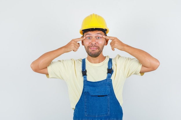 Photo gratuite jeune ingénieur plissant les yeux en uniforme et l'air fatigué, vue de face.