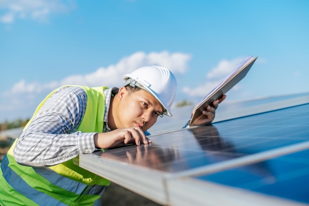 Photo gratuite jeune inspecteur asiatique ingénieur homme travaillant à la ferme solaire technicien ou superviseur masculin en casque blanc vérification du fonctionnement du soleil et du panneau solaire photovoltaïque dans l'espace de copie de la station