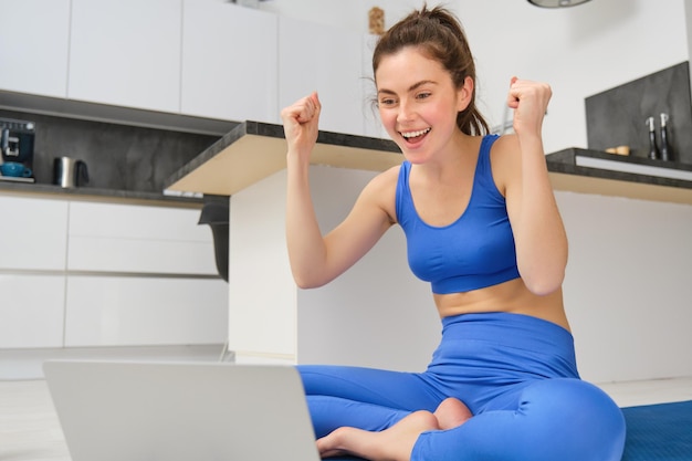 Photo gratuite un jeune instructeur de fitness heureux célèbre les réalisations de ses clients en se réjouissant tout en regardant un ordinateur portable