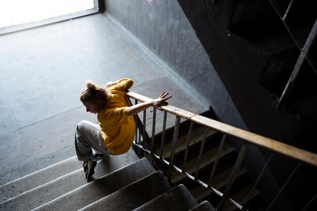 Jeune interprète féminine dansant dans un bâtiment abandonné dans les escaliers