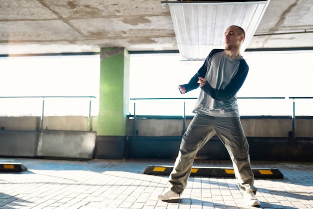 Jeune interprète masculin dansant dans un parking avec des pilons