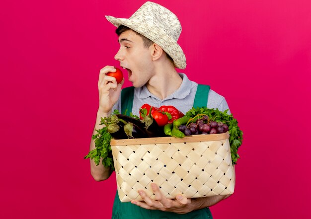 Un jeune jardinier joyeux portant un chapeau de jardinage tient un panier de légumes