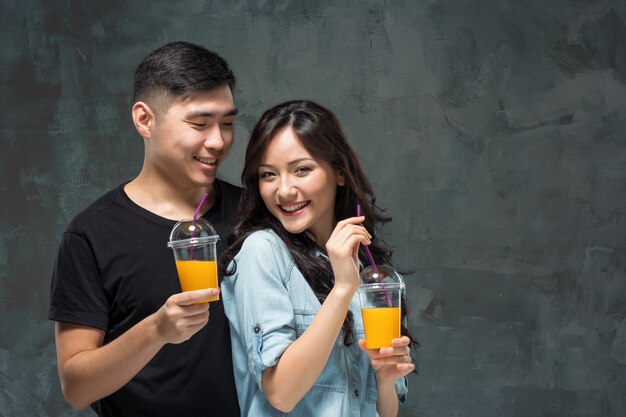 Un jeune joli couple asiatique avec un verre de jus d'orange