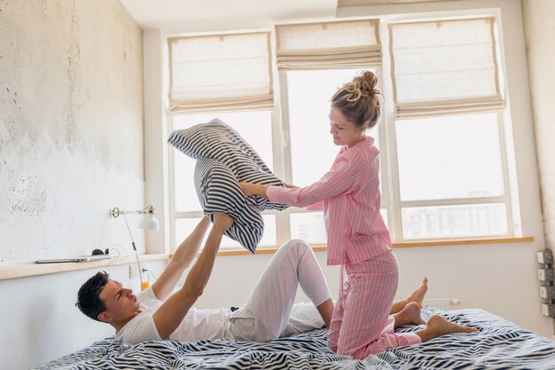 Jeune joli couple s'amusant sur le lit le matin rester ensemble à la maison seul