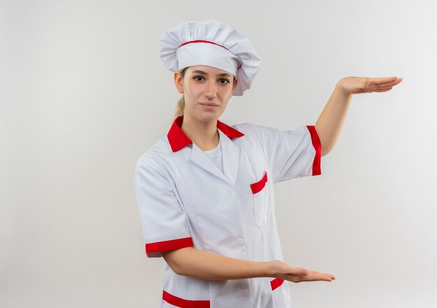 Jeune jolie cuisinière en uniforme de chef montrant la taille à la recherche