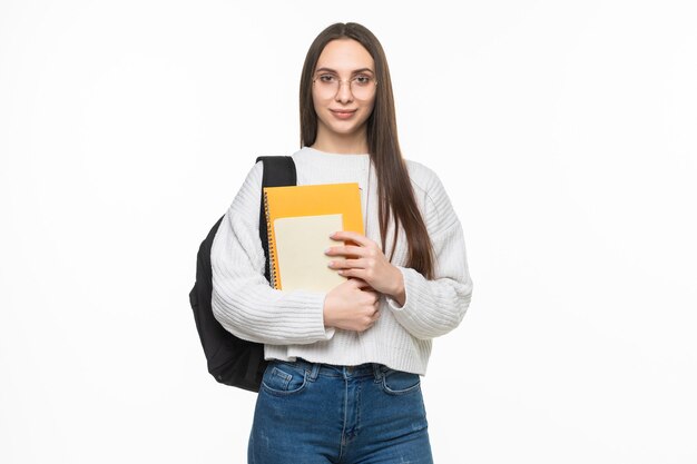 Jeune jolie étudiante avec sac à dos et cahiers. isolé sur mur blanc