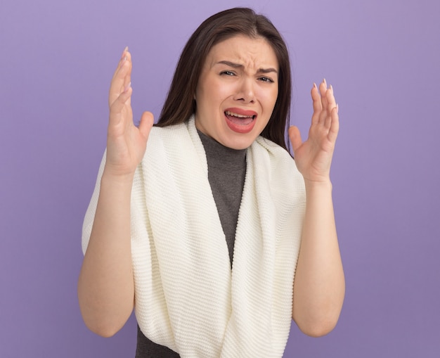 Jeune jolie femme agacée gardant les mains en l'air isolées sur un mur violet