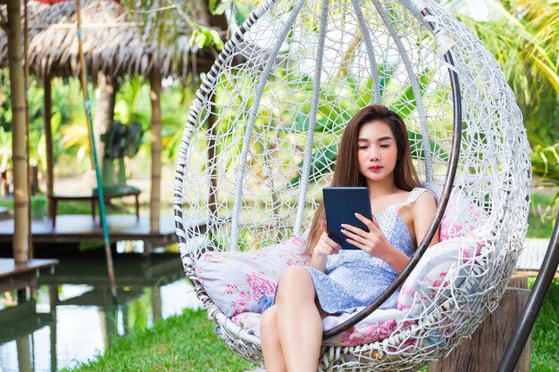 Jeune jolie femme assise utilise un ordinateur portable en balançoire