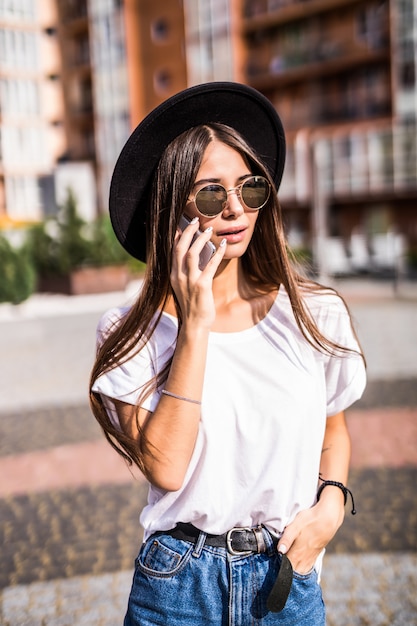 Jeune jolie femme au chapeau noir parler téléphone sur la rue d'été